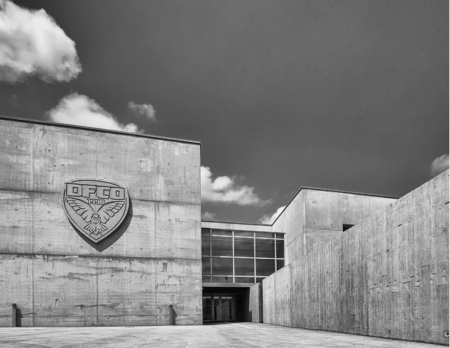 Bâtiment moderne avec logo architectural et entrée vitrée en béton brut