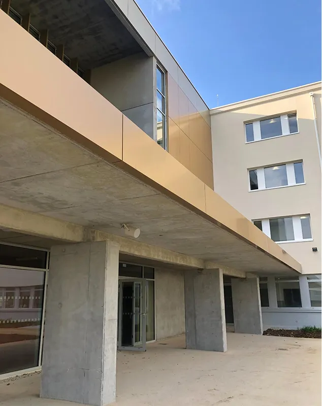 Bâtiment moderne avec structure en béton et façade beige-ocre sous ciel dégagé