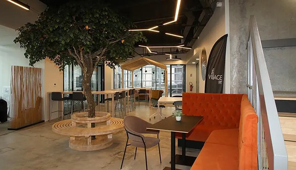 Espace coworking moderne avec arbre central et mobilier design dans agence architecturale